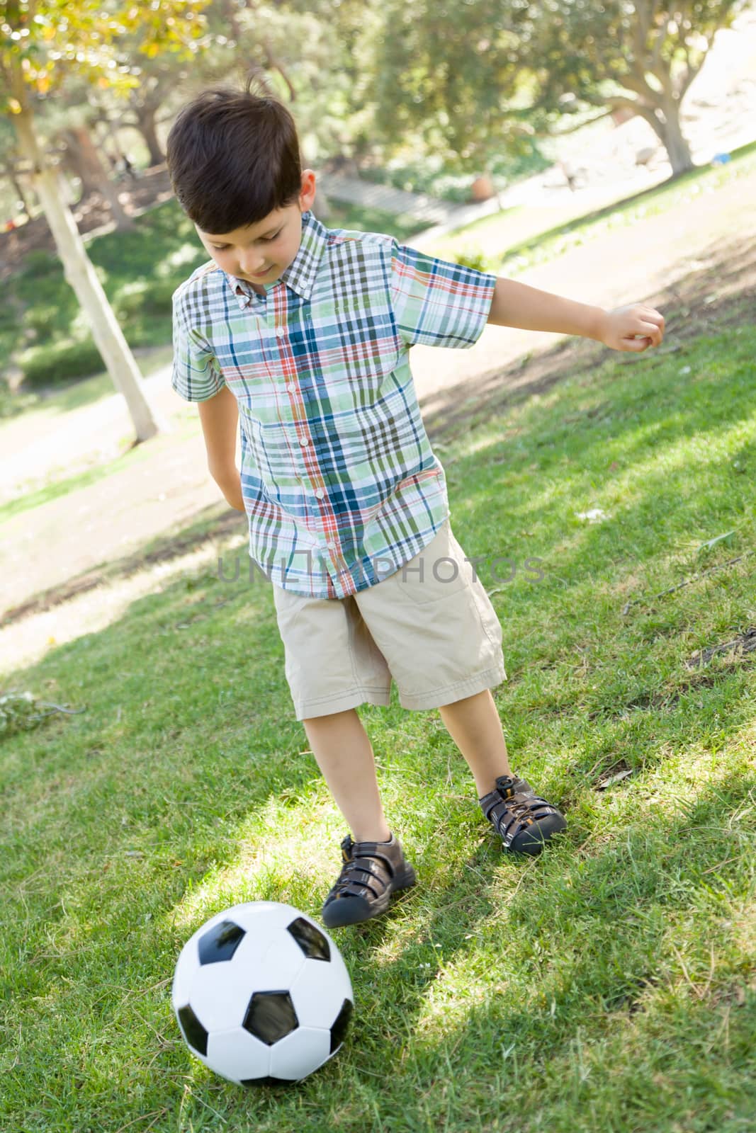 Cute Young Boy Playing with Soccer Ball Outdoors in the Park.