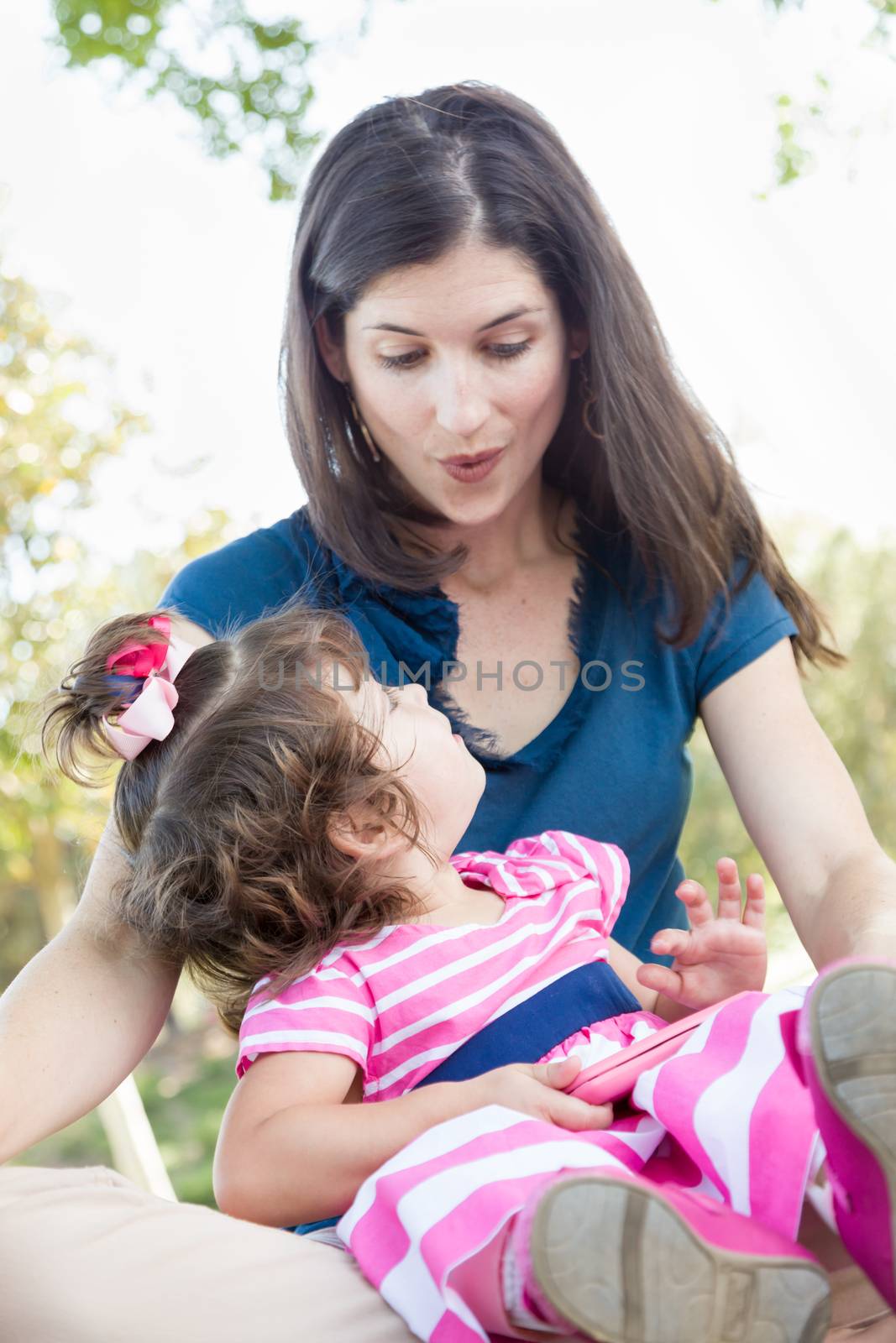 Mixed Race Mother and Cute Baby Daughter Playing with Cell Phone in Park.