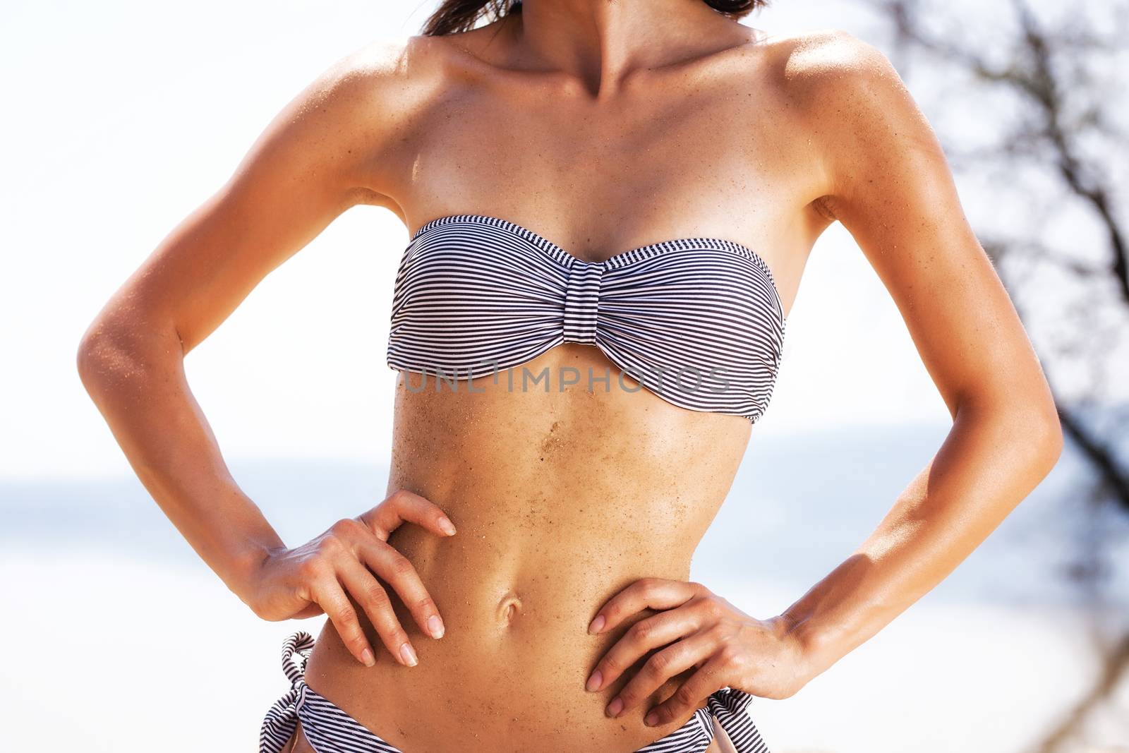 sexy female body on a beach, with sand on the belly