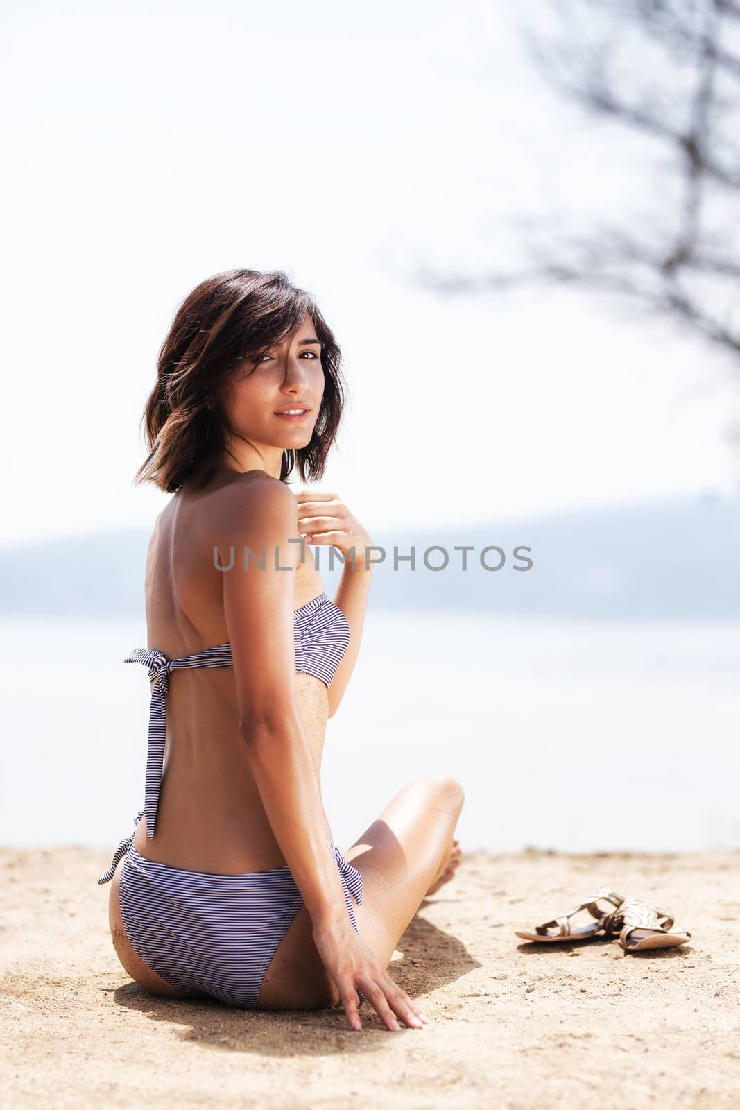 sexy girl with sunglasses and slippers sunbathing on a beach