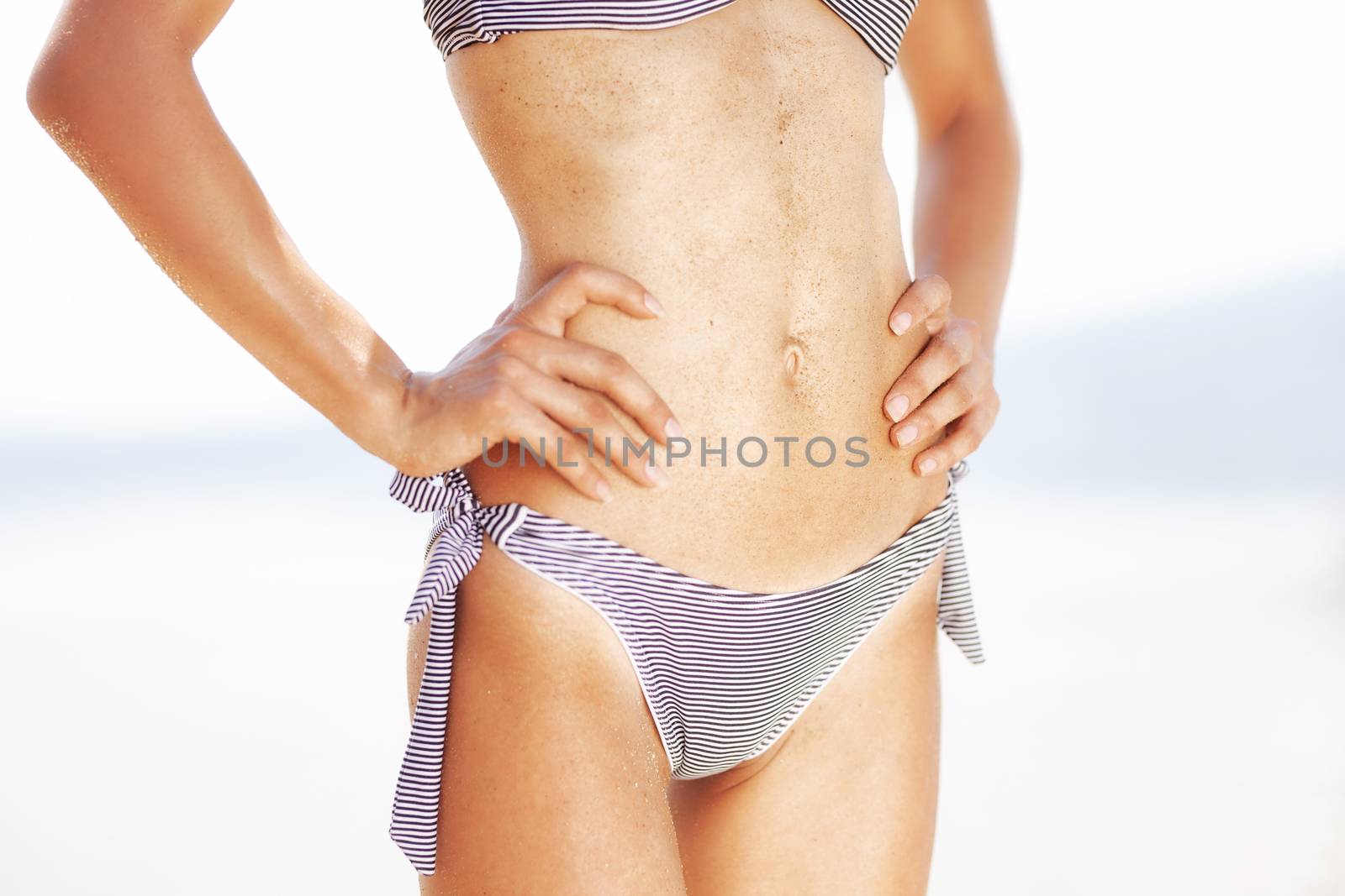 sexy female body on a beach, with sand on the belly