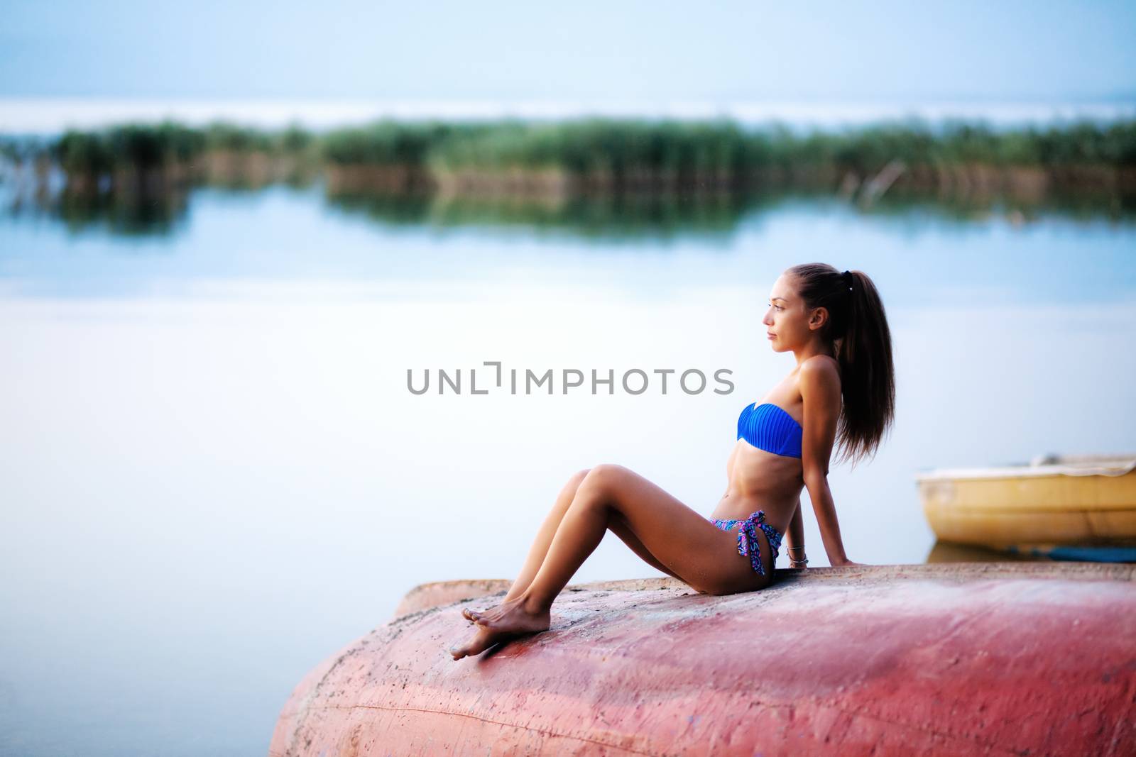 girl on an upside down rowboat shot at sunset by kokimk