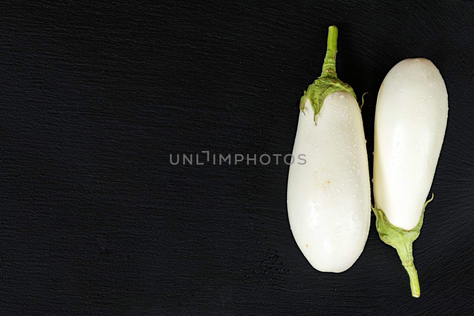 White eggplant on a black stone surface with water drops. Top vi by ArtSvitlyna