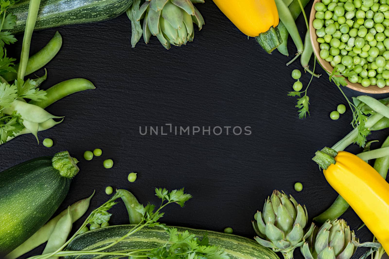 Fresh organic green vegetables on black stone floor with copy space. Green and yellow vegetables background. Healthy eating background. Vegetarian food, organic food.