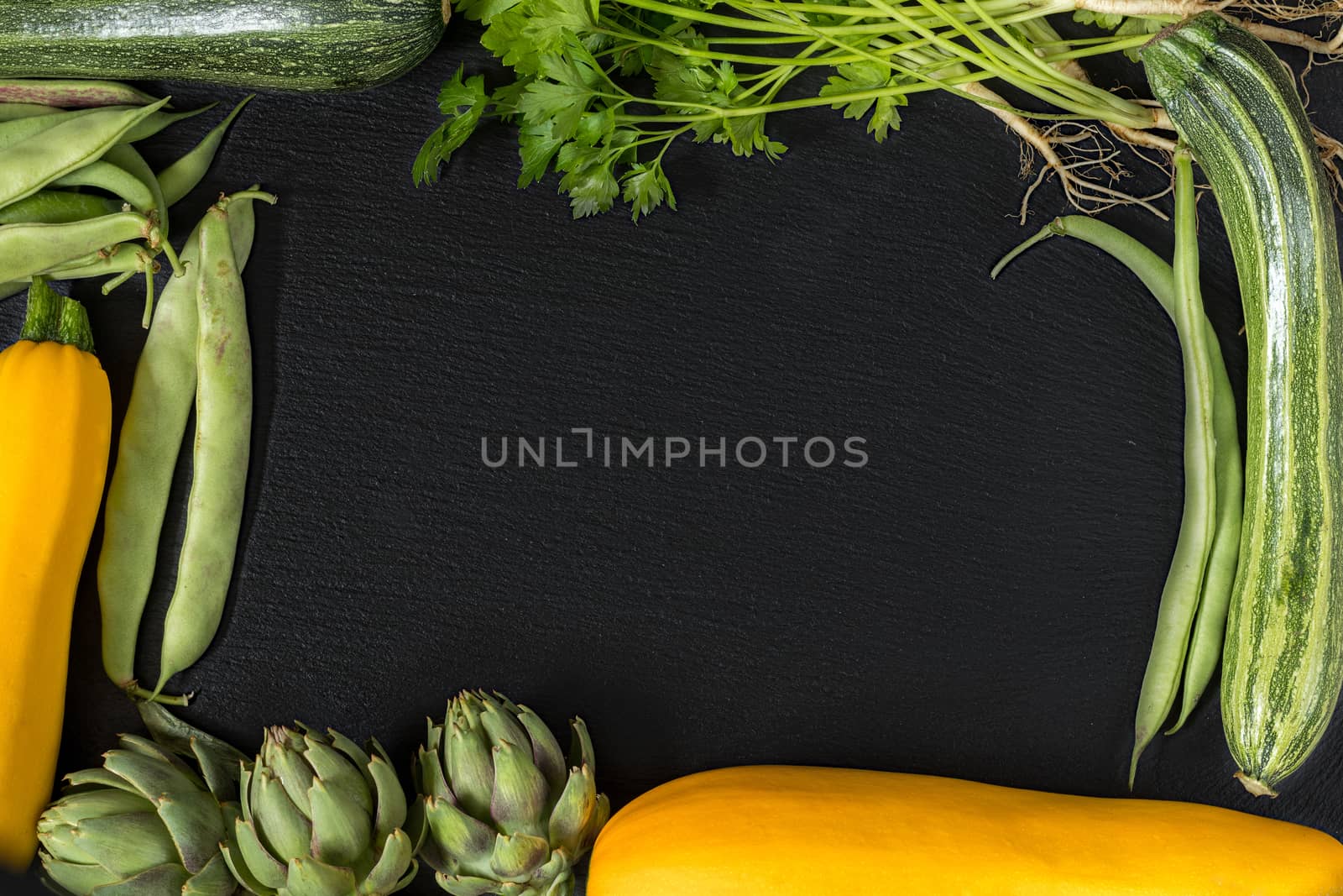 Fresh organic green vegetables on black stone floor by ArtSvitlyna