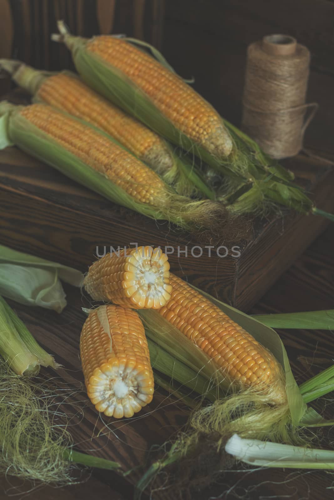 Fresh sweet corn on cobs on rustic wooden table, close up. Toned. Shallow depth of field.