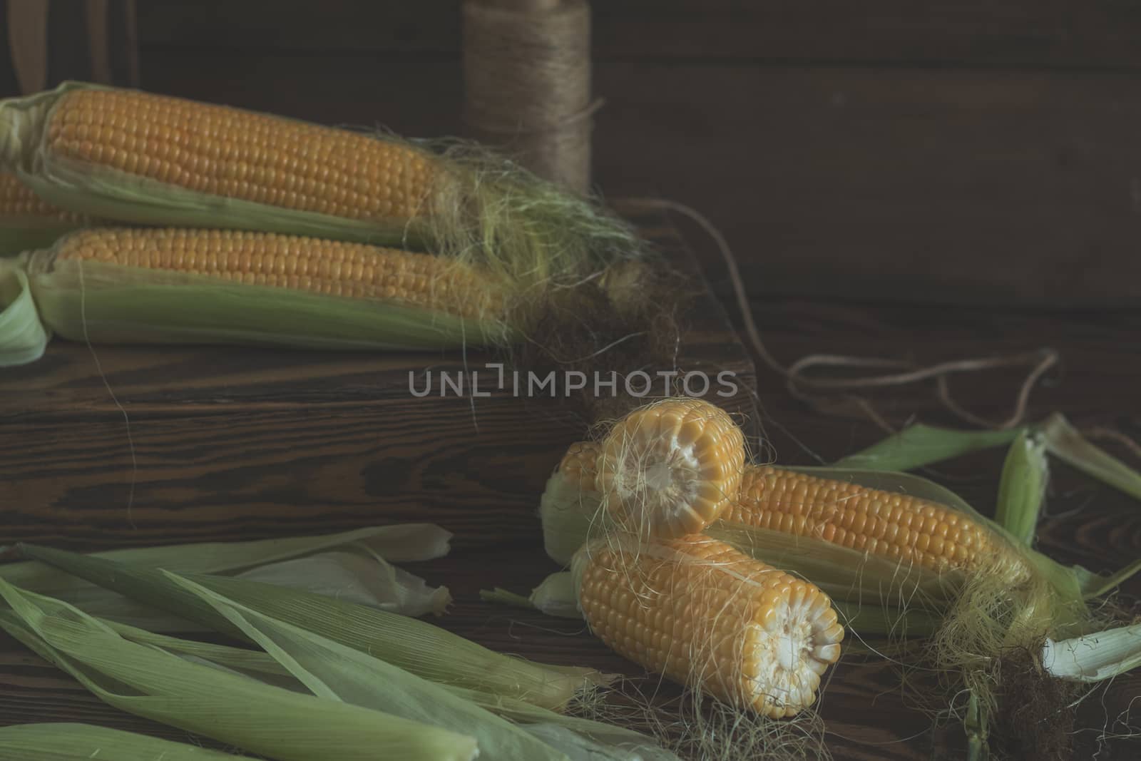 Fresh sweet corn on cobs on rustic wooden table, close up. Toned. Shallow depth of field.