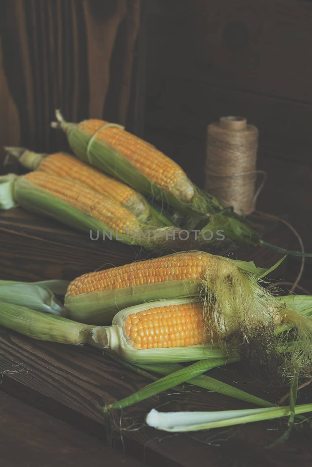 Fresh sweet corn on cobs on rustic wooden table, close up. Toned. Shallow depth of field.