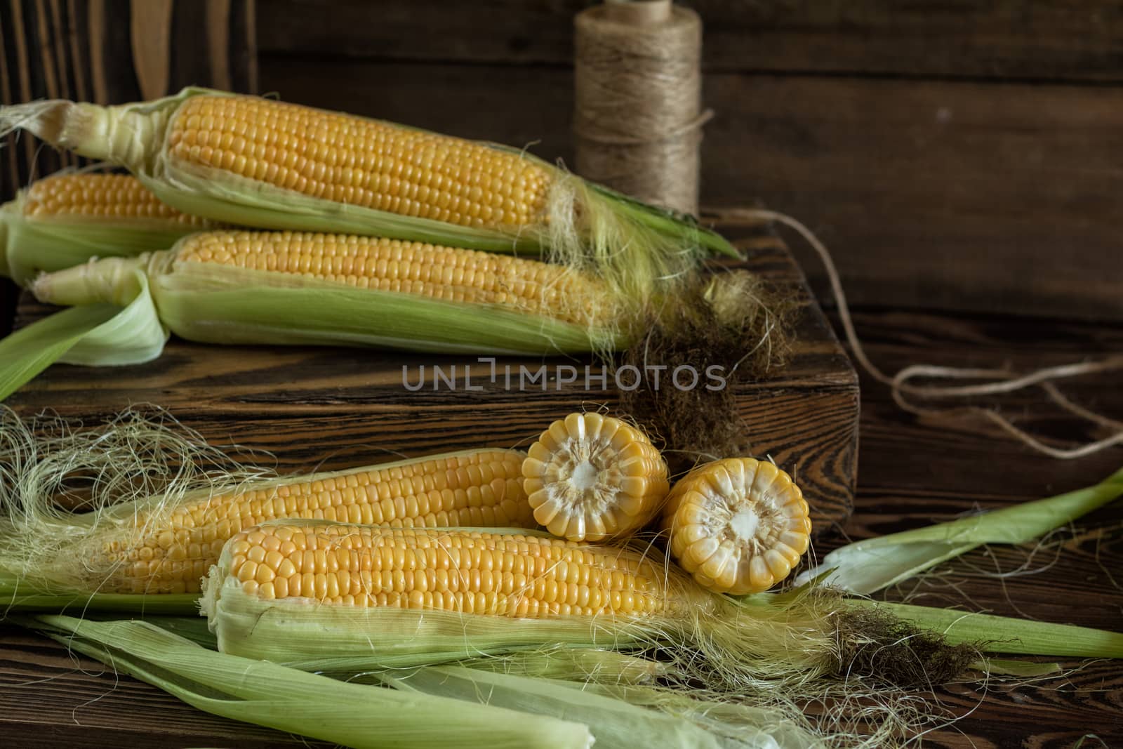 Fresh sweet corn on cobs on rustic wooden table, close up. Toned. Shallow depth of field.