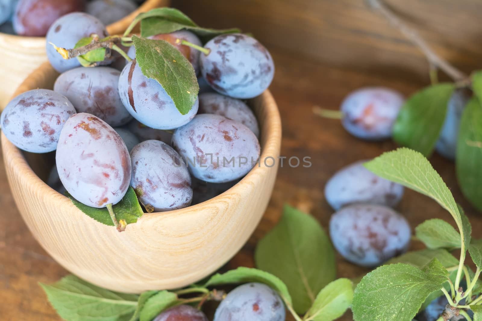 Fresh plums on wooden table by ArtSvitlyna