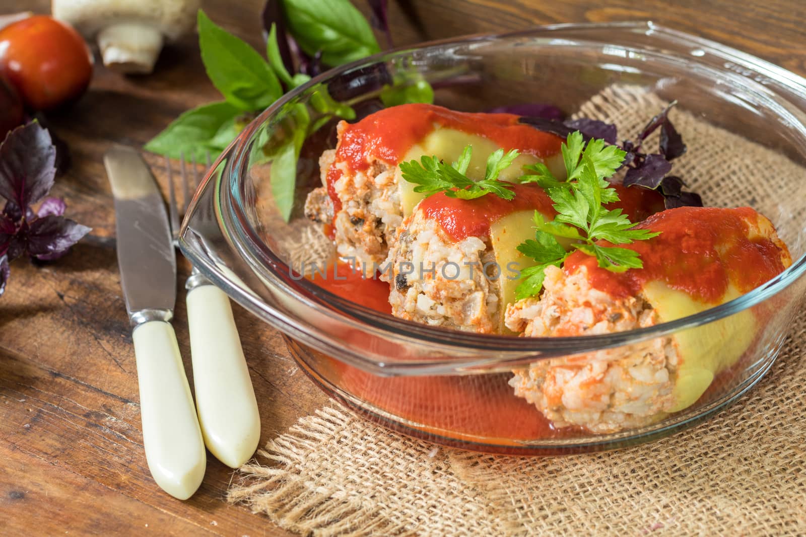 Yummy looking cooked stuffed pepper served in a transparent glass pot on a wooden table