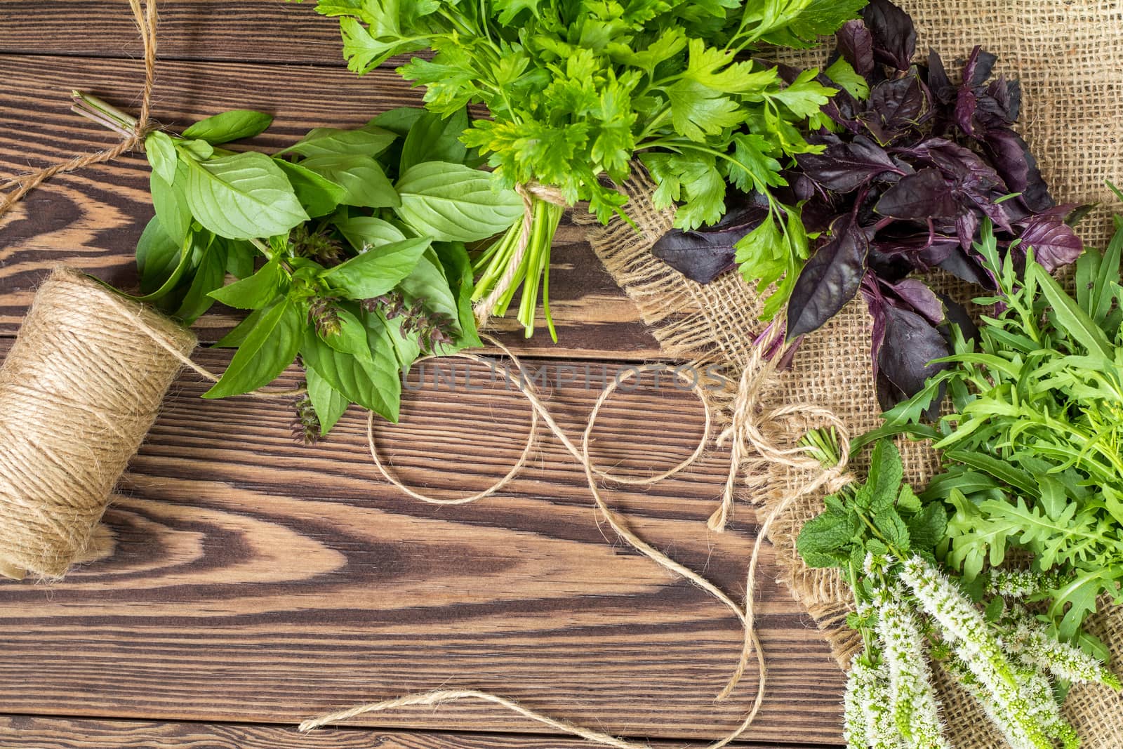 Fresh organic green herbs wooden floor with copy space. Green and violet plants background. Healthy eating background. Vegetarian food, organic food.