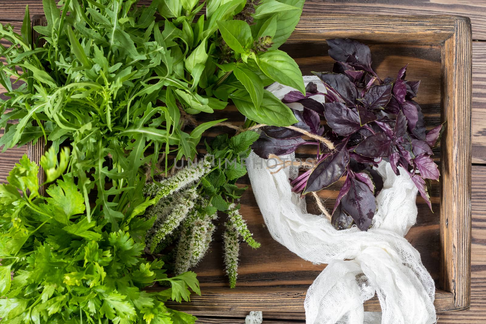 Fresh organic green herbs wooden floor with copy space. Green and violet plants background. Healthy eating background. Vegetarian food, organic food.