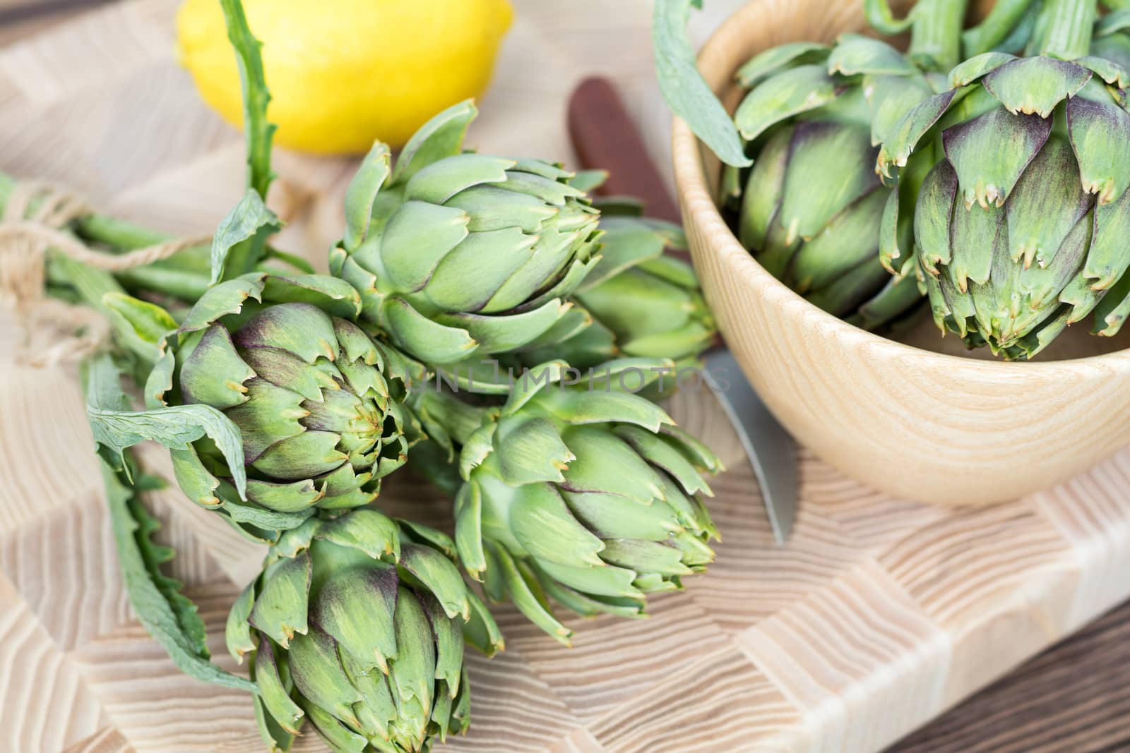 Two artichoke bouquets on kitchen table among some kitchen items. Top view.