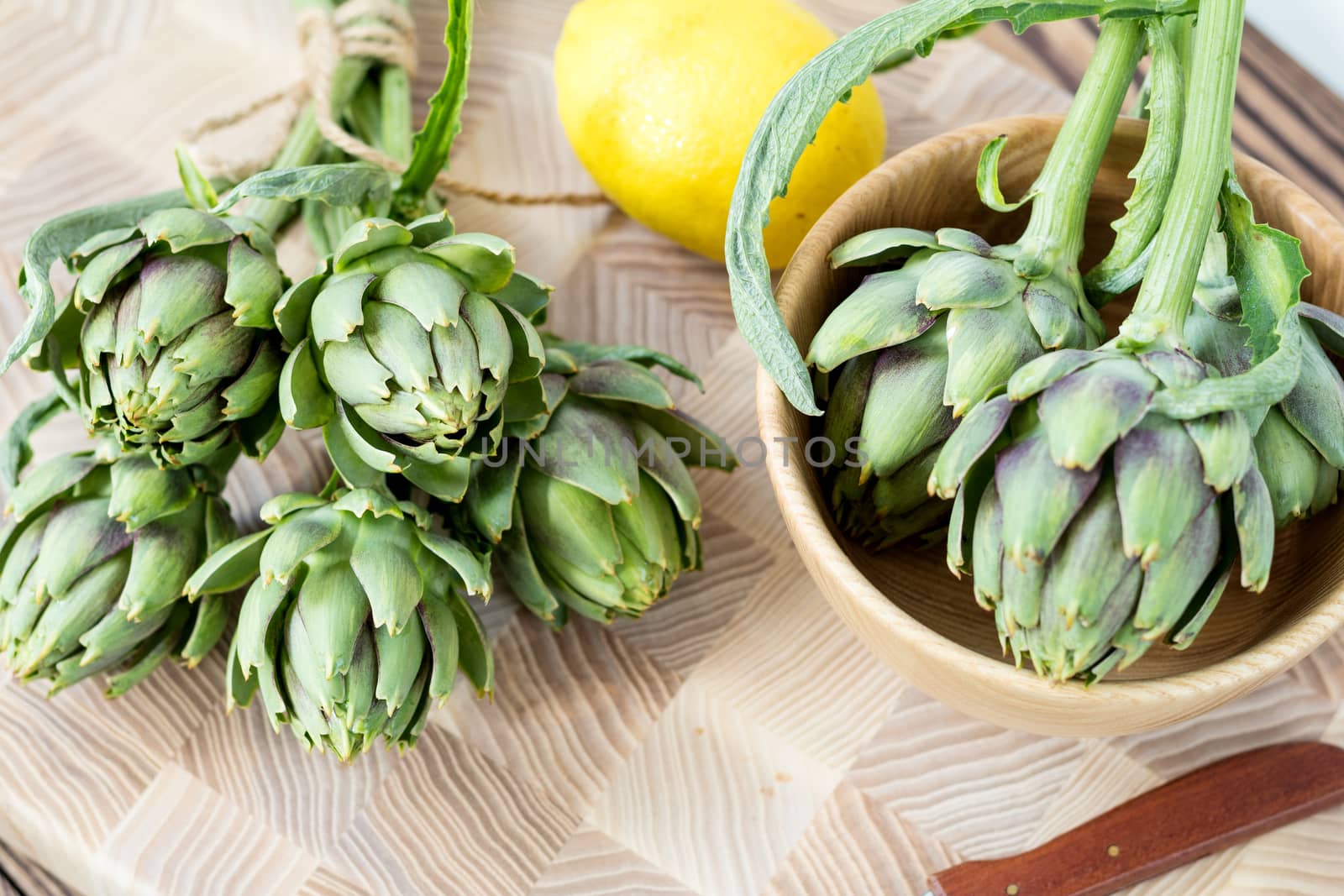Two artichoke bouquets on kitchen table among some kitchen items. Top view