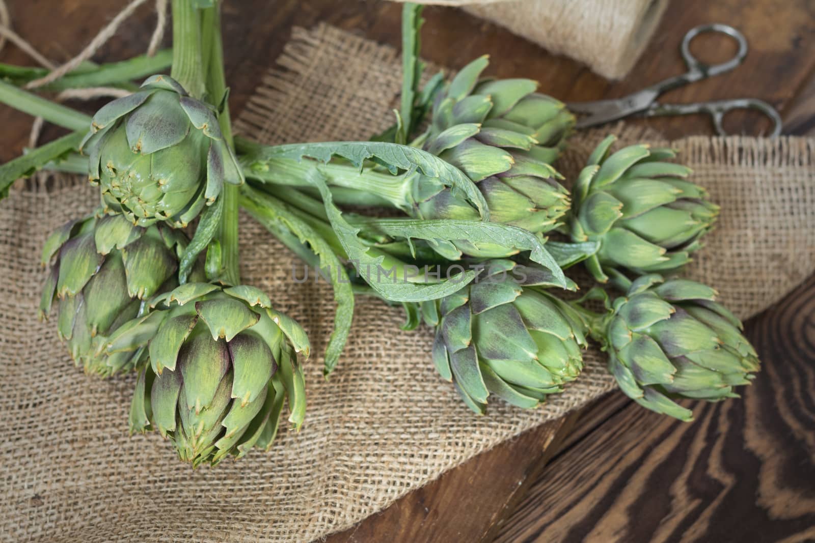 Two artichoke bouquets on sackcloth on wooden background. Top view.