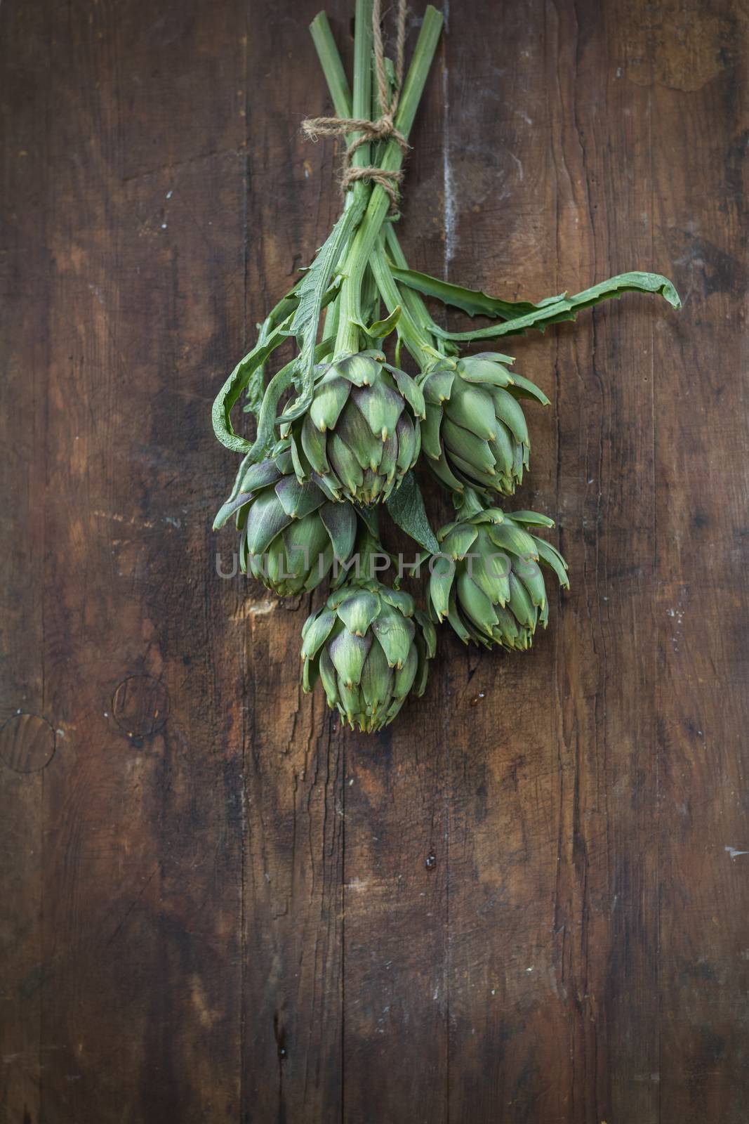 Supplies and materials for artichoke bouquet on wooden background.