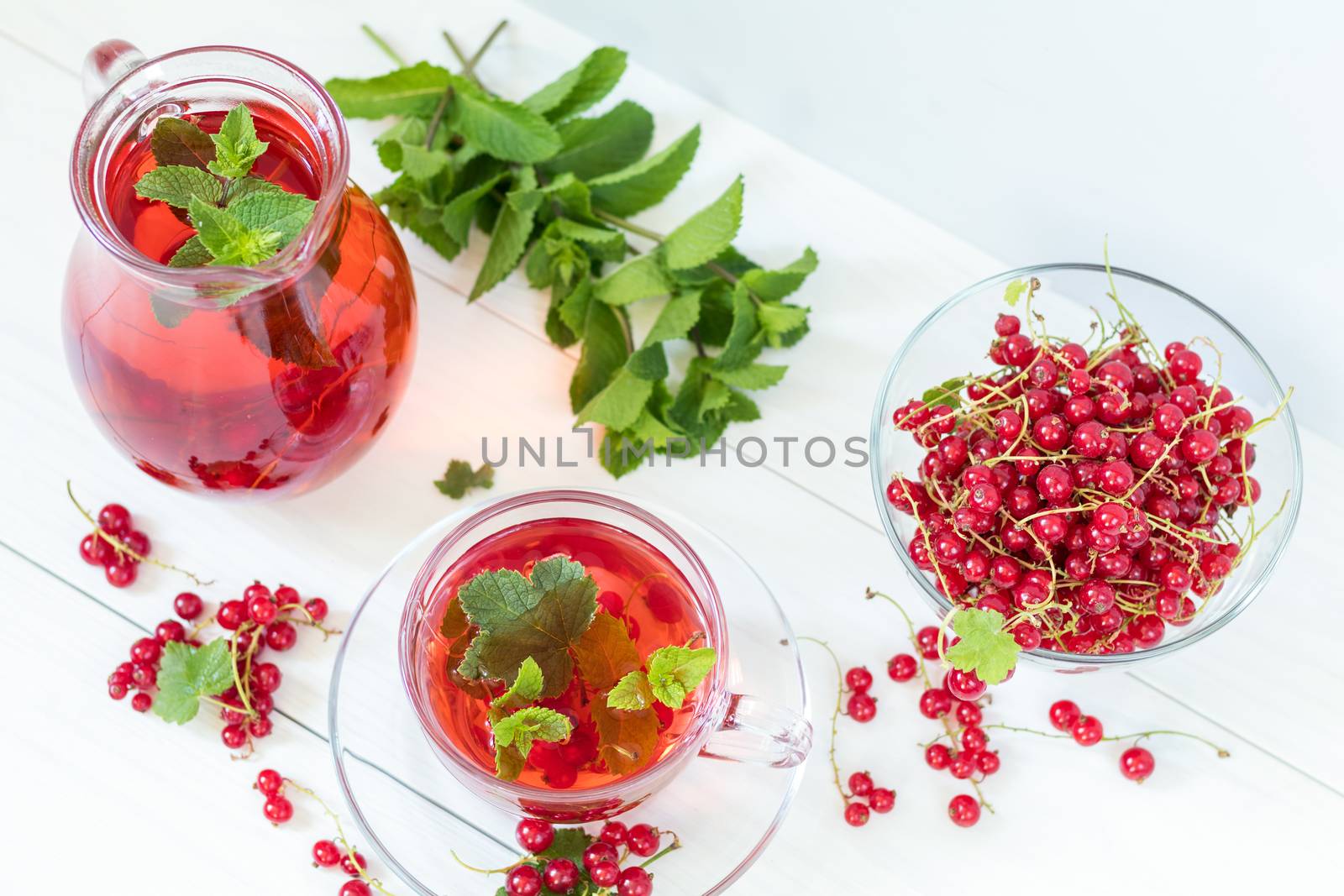 Redcurrant drink in transparent glass carafe and cup by ArtSvitlyna