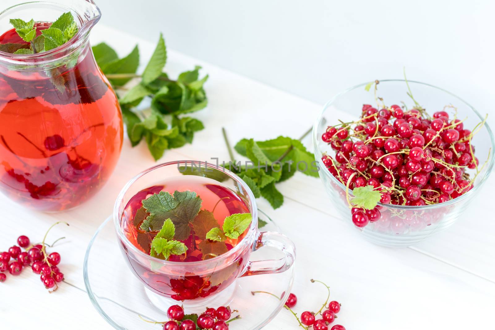 Redcurrant drink in transparent glass carafe and cup. Clear glas by ArtSvitlyna