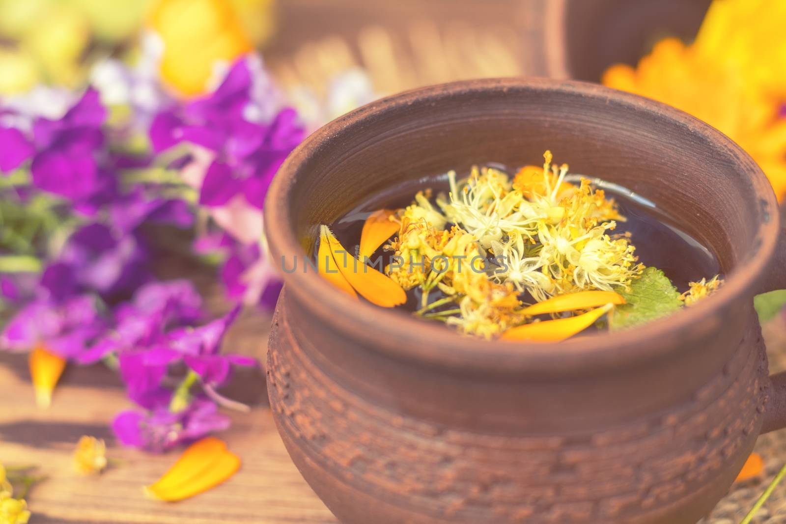 Two ceramic cups of healthy herbal tea with decoction of dry and fresh flowers on dark aged rustic wooden background. Shallow depth of field.