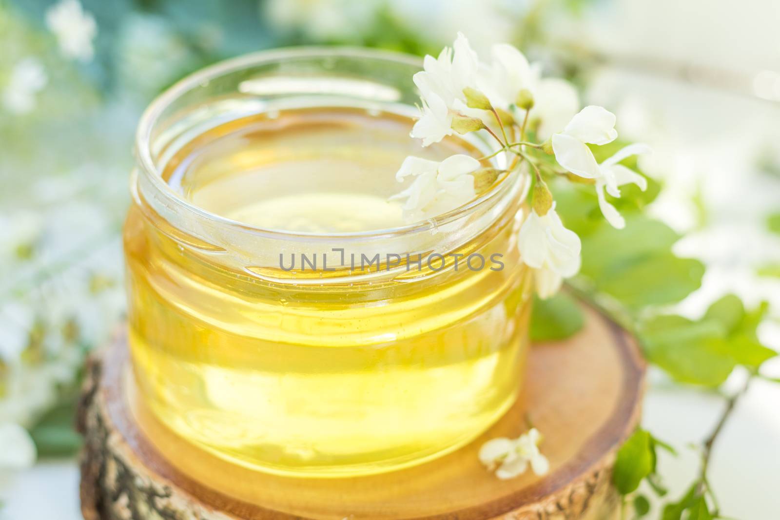 Honey in glass jars with acacia blossoms on windowsill. Shallow depth of field.