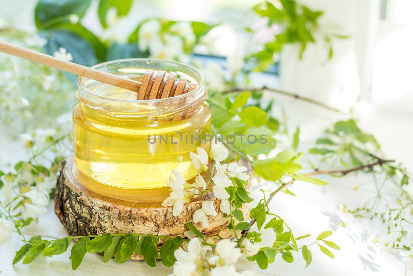 Honey in glass jars with acacia blossoms on windowsill. Shallow depth of field.