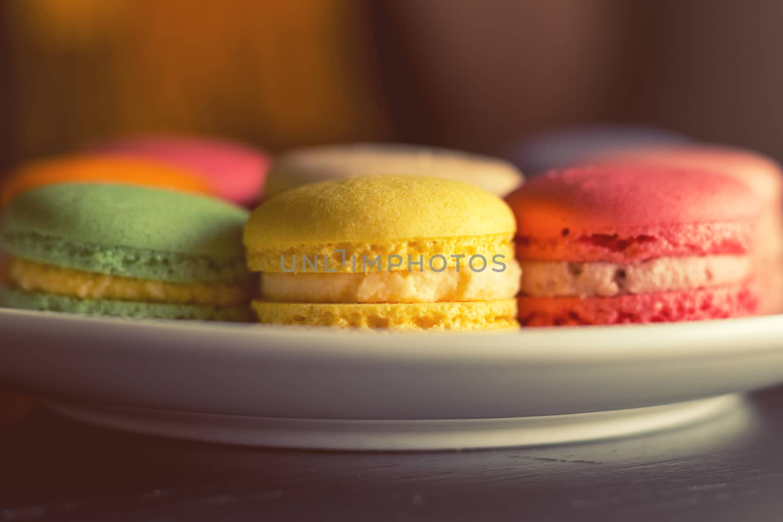 Colorful multicolor sweet delicious macaroons on dark background. Shallow depth of field. Coloring toned photo.