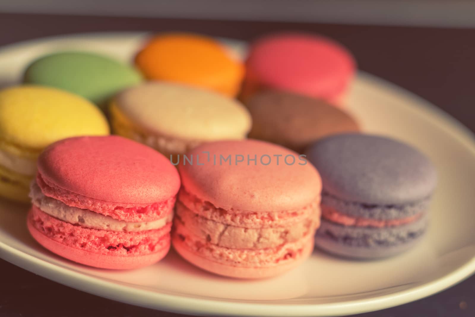 Colorful multicolor sweet delicious macaroons on dark background. Shallow depth of field. Coloring toned photo.