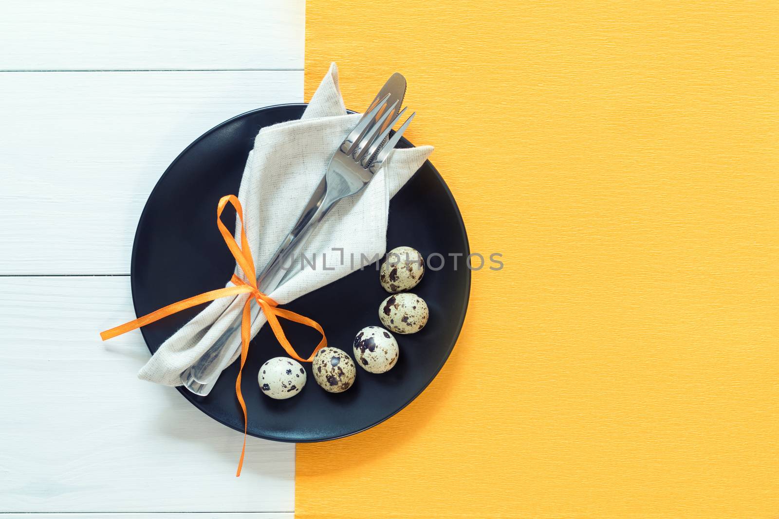 Easter table setting with cutlery. Rustic orange table cloth on white wood background. Holidays background with copy space.