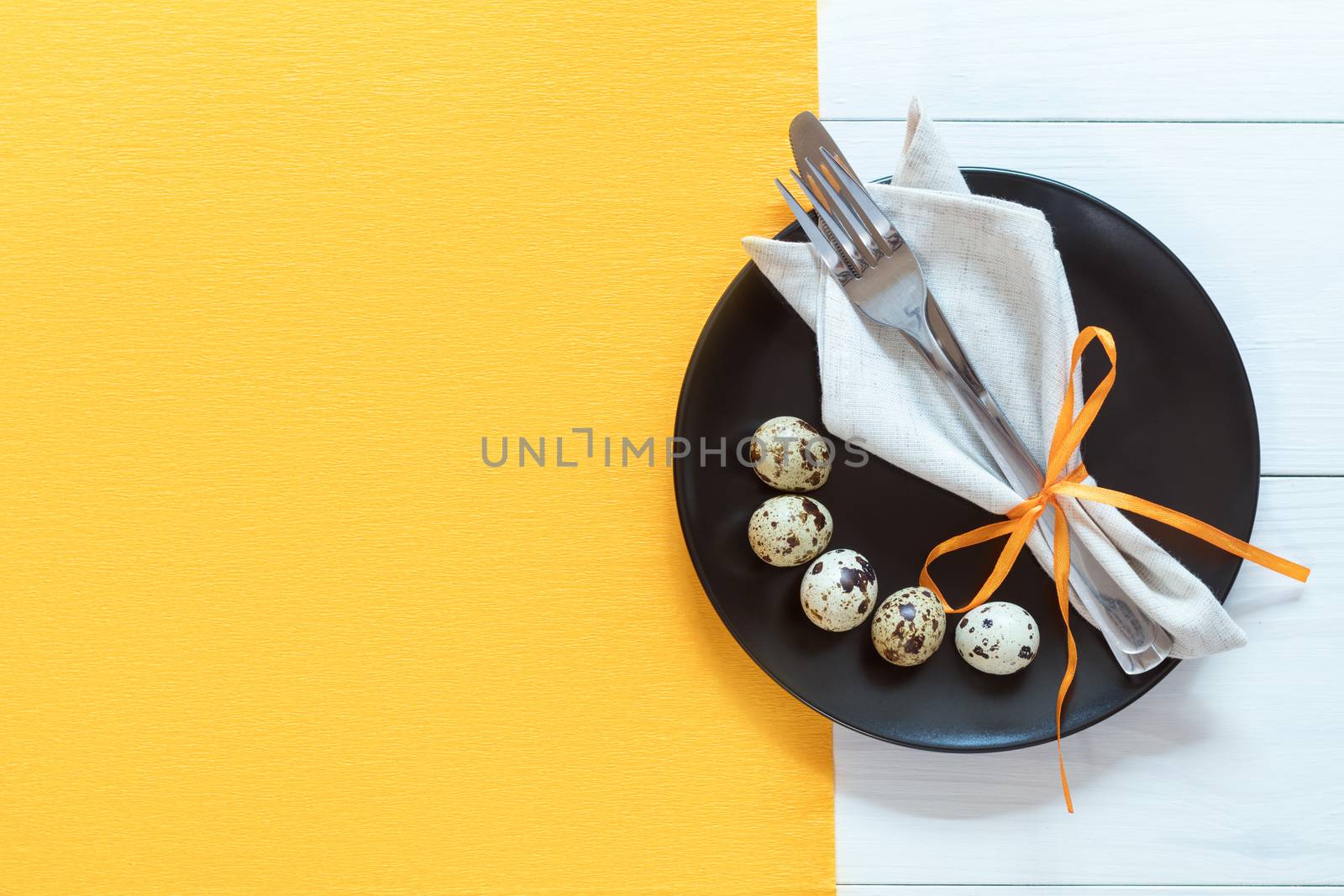 Easter table setting with cutlery. Rustic orange table cloth on white wood background. Holidays background with copy space.