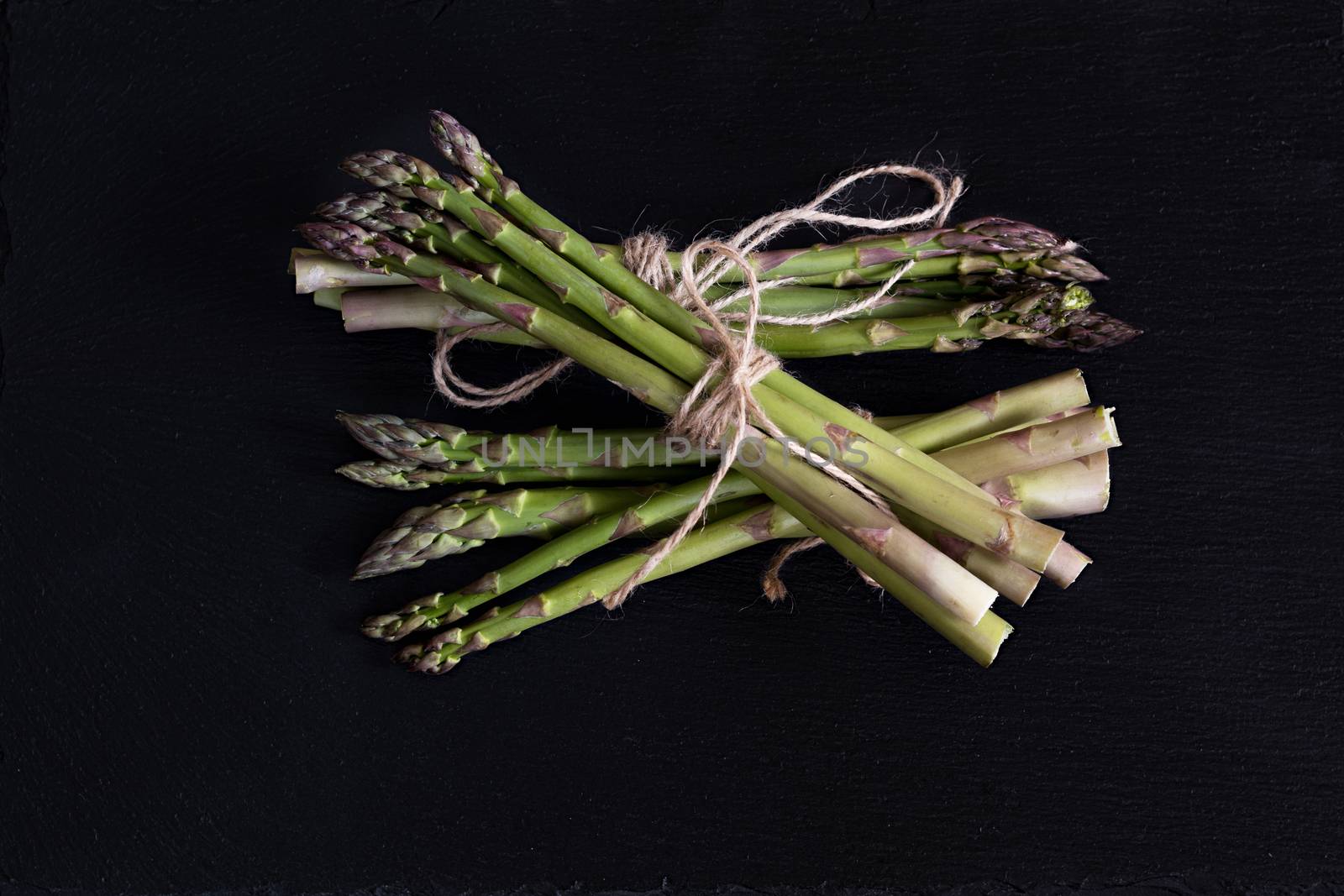 Bunch of fresh green asparagus spears on a black stone background