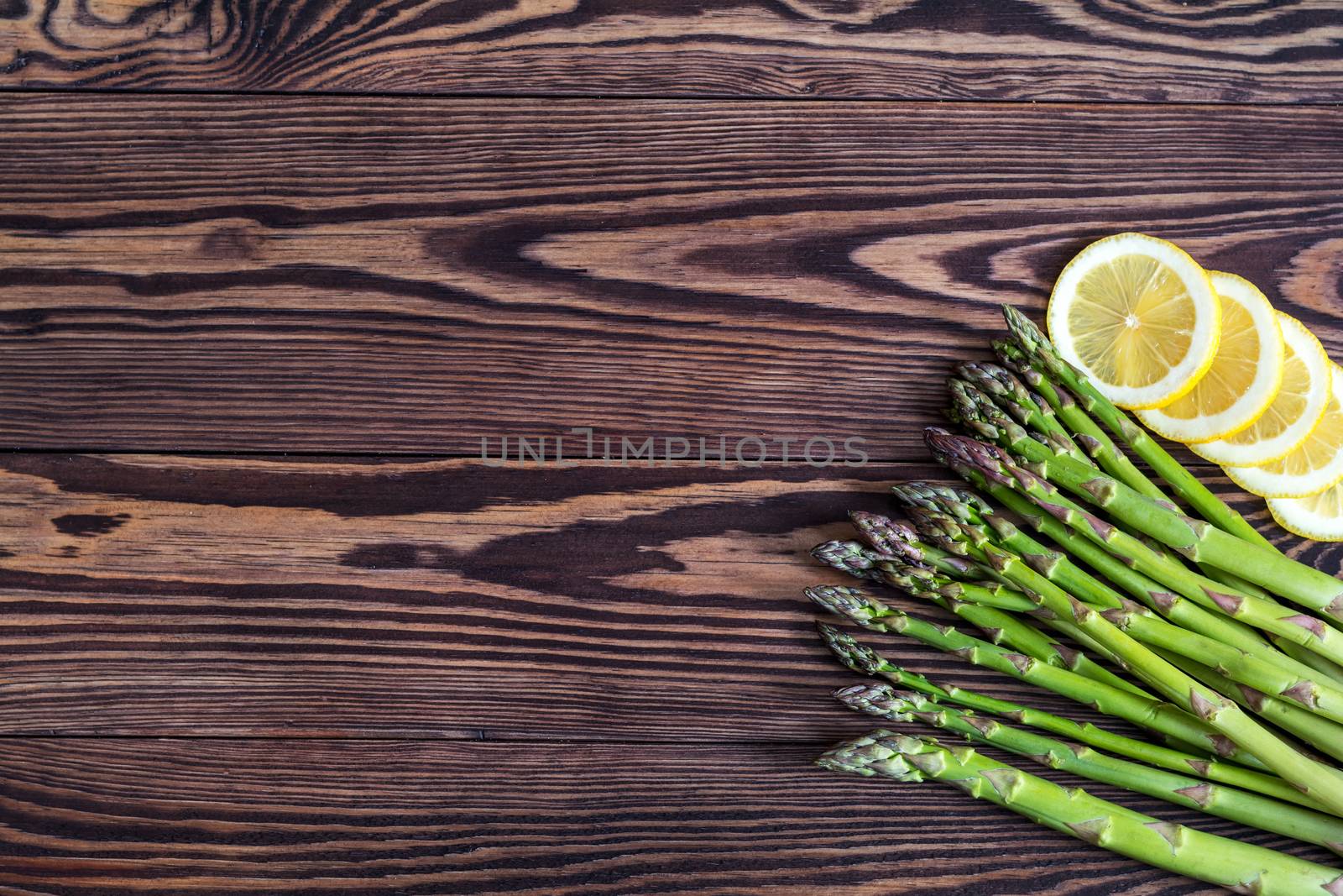 Bunch of fresh green asparagus spears and lemon on a rustic wooden table
