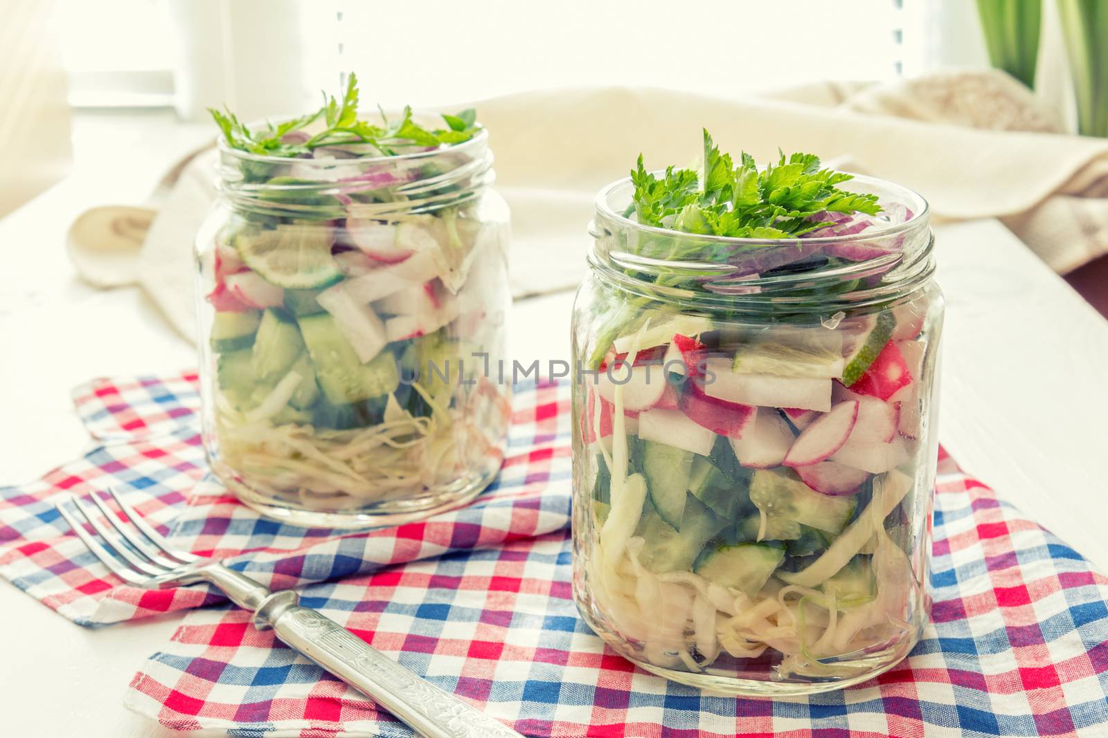 Homemade healthy salads with vegetables, onion, parsley and lettuce in jar. Toning. Selective focus.