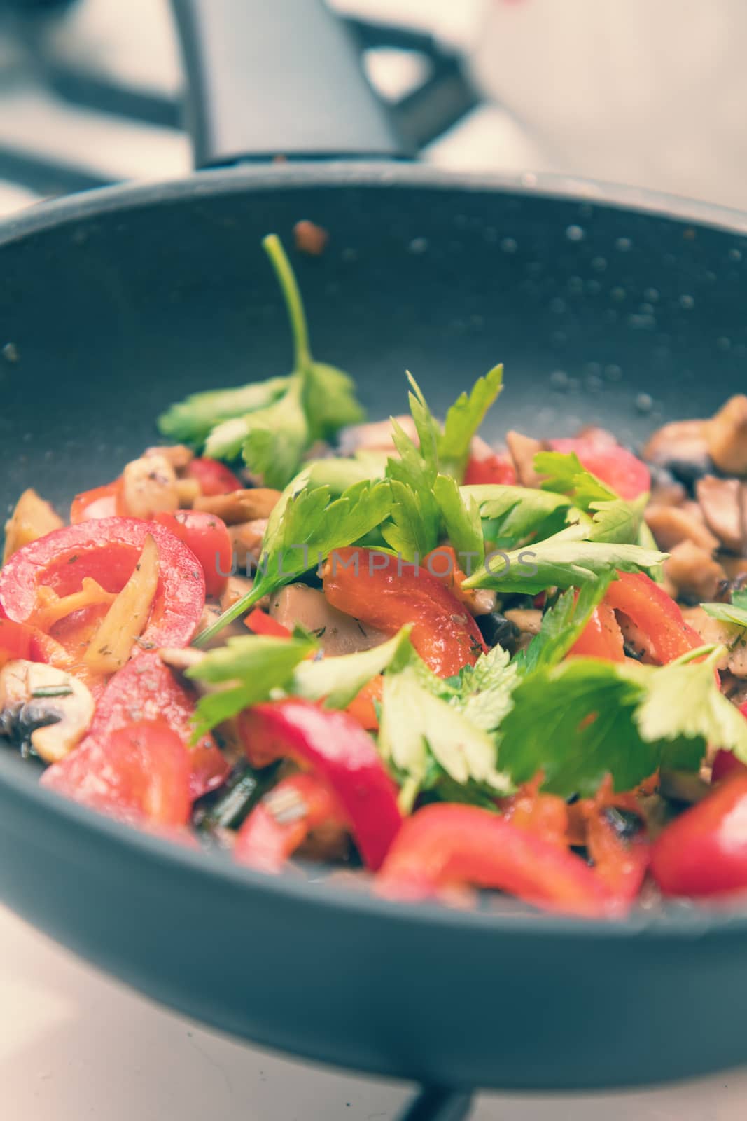 Mushrooms and fresh sweet red pepper in the pan for cooking. Spices and fresh parsley. Shallow depth of field. Toned