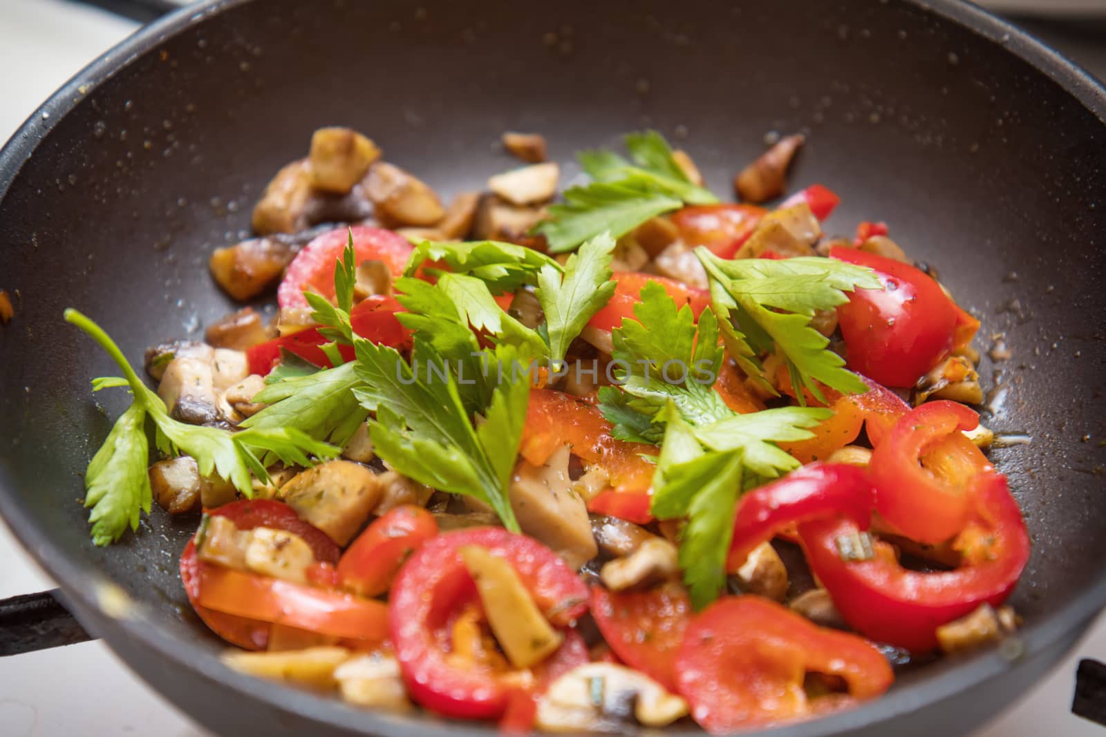 Mushrooms and fresh sweet red pepper in the pan for cooking. Spices and fresh parsley. Shallow depth of field. Toned