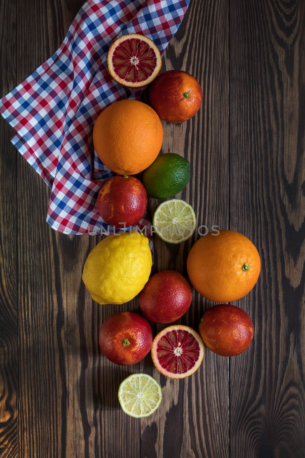 Sicilian Blood oranges, oranges, lemons and limes fruits over old dark wooden background. Top view. Toned.