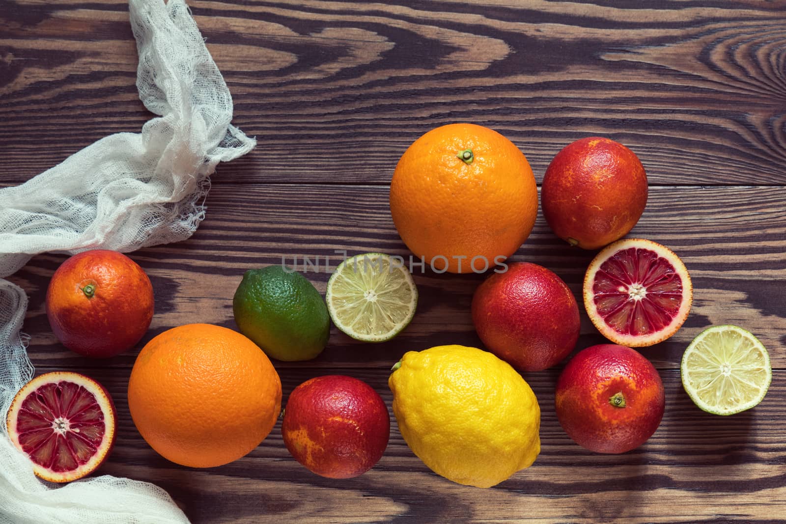 Sicilian Blood oranges, oranges, lemons and limes fruits over old dark wooden background. Top view. Toned.