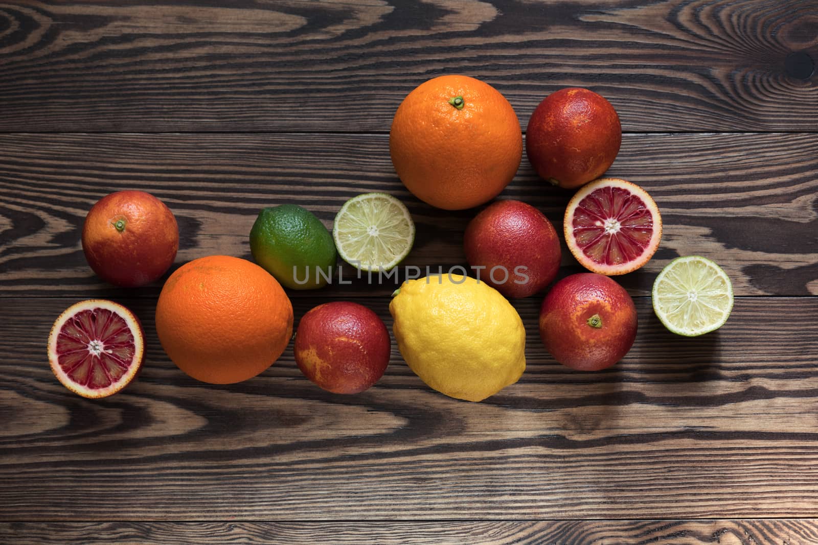 Sicilian Blood oranges, oranges, lemons and limes fruits over old dark wooden background. Top view. Toned.