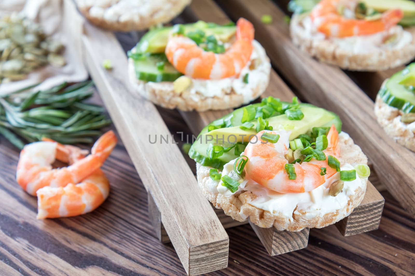 Rice cakes with sliced avocado cucumber shrimp and cream cheese.  Fresh parsley and rosemary. Vegetarian, vegan concept. Shallow depth of field. Coloring and processing photo.