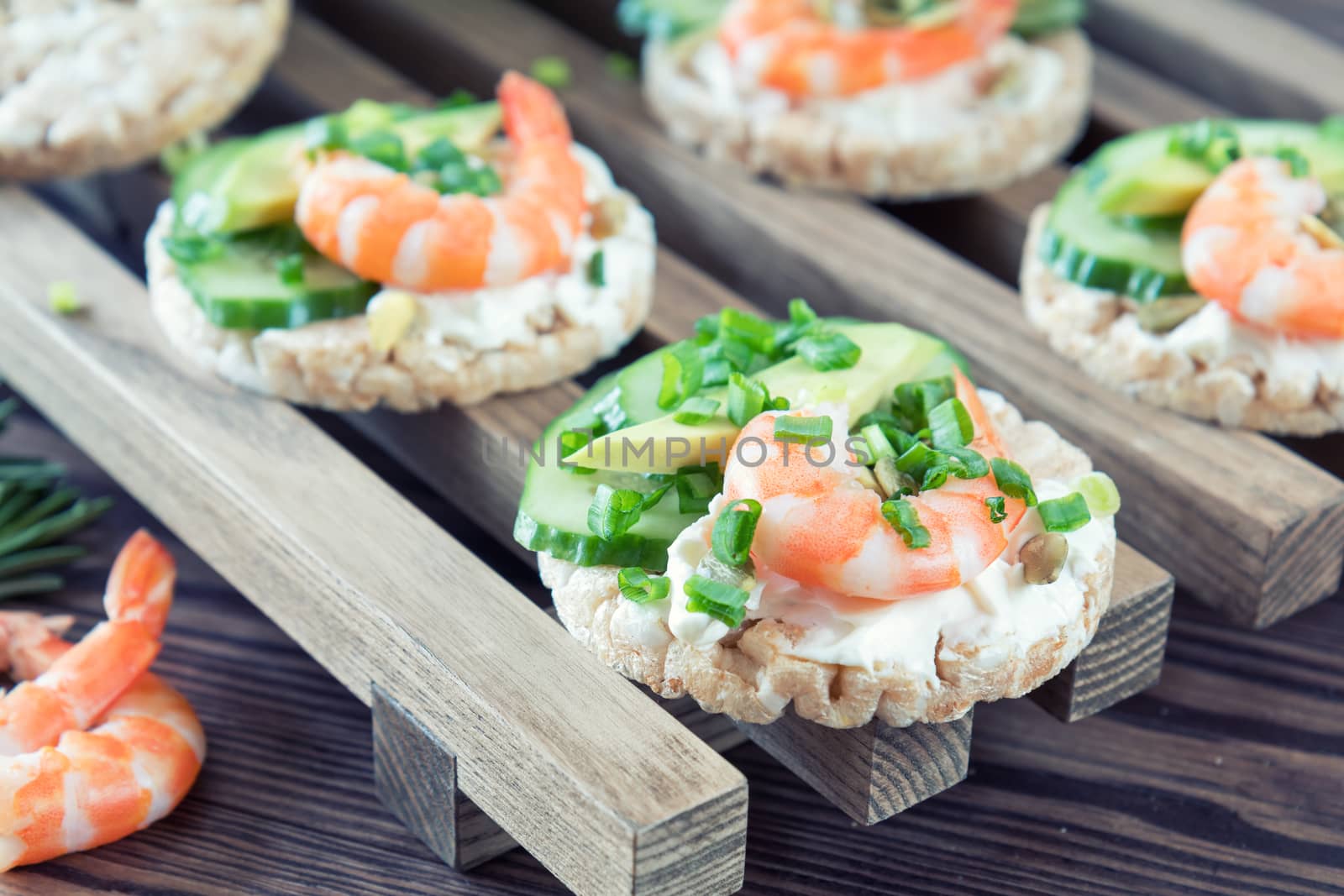 Rice cakes with sliced avocado cucumber shrimp and cream cheese.  Fresh parsley and rosemary. Vegetarian, vegan concept. Shallow depth of field. Coloring and processing photo.