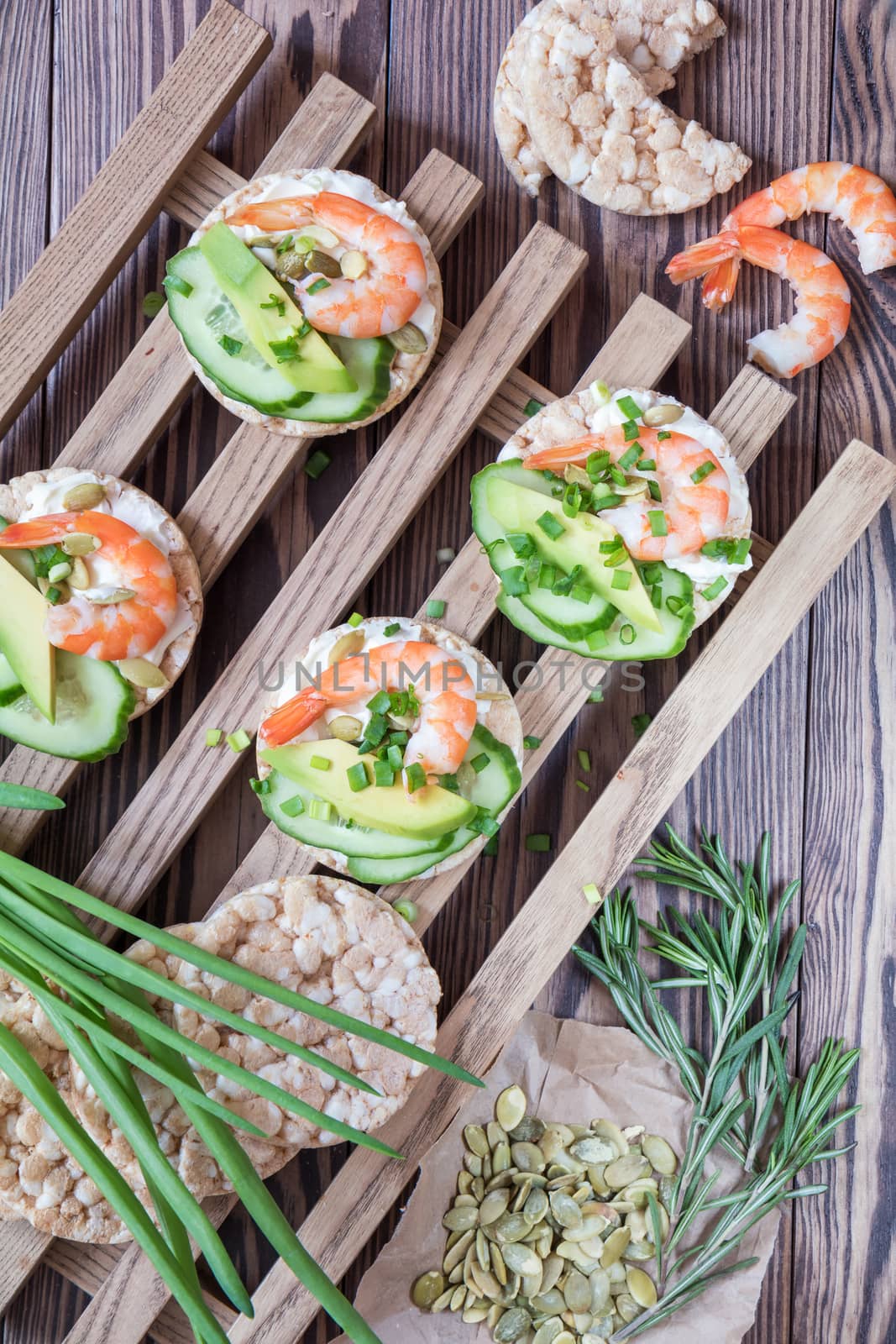 Rice cakes with sliced avocado cucumber shrimp and cream cheese.  Fresh parsley and rosemary. Vegetarian, vegan concept. Shallow depth of field. Coloring and processing photo.