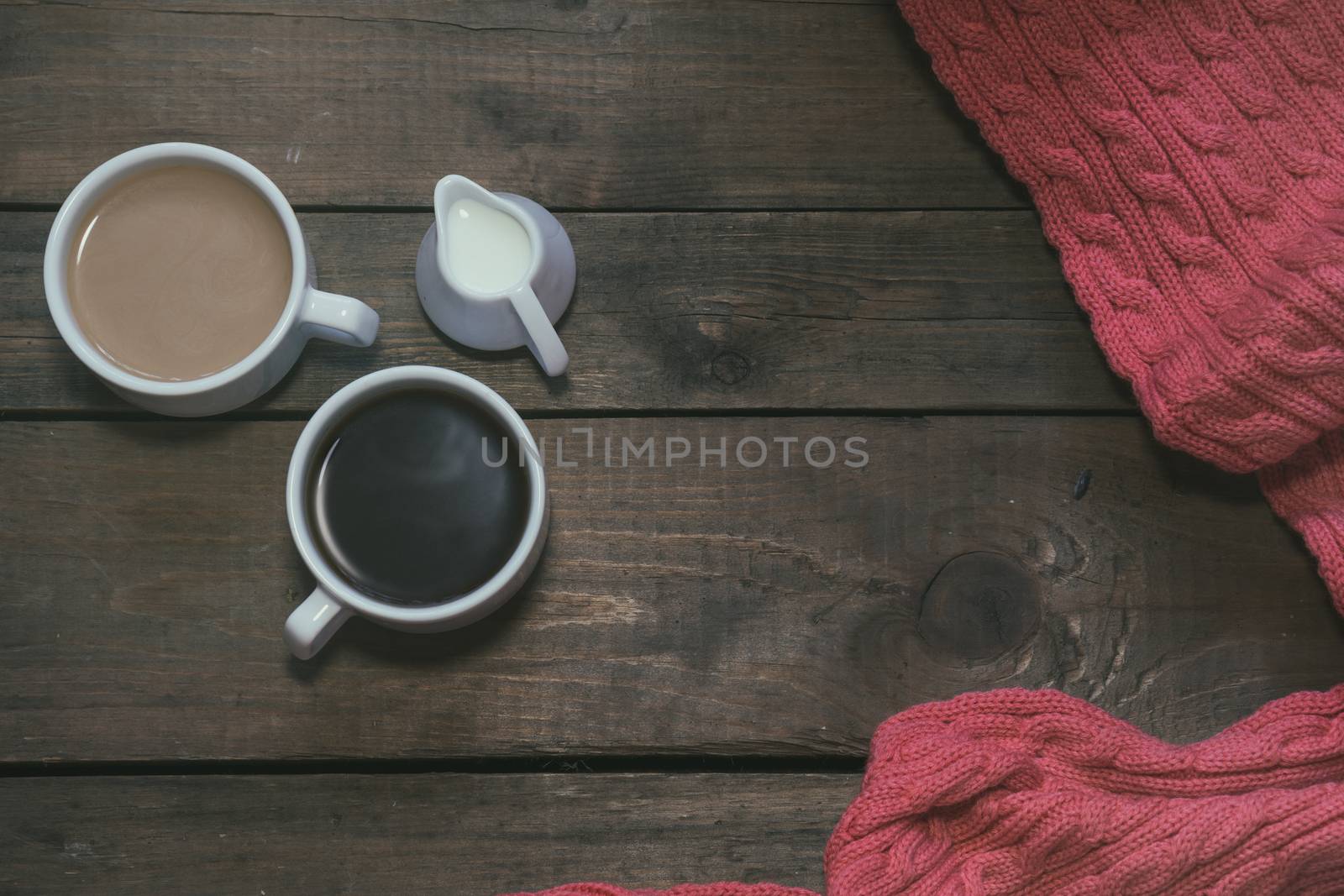 Cup of black coffee, cup of coffee with milk, cream. Pink woven scarf. Dark wooden background. Beautiful vintage coffee groundwork. Coloring and processing photo.