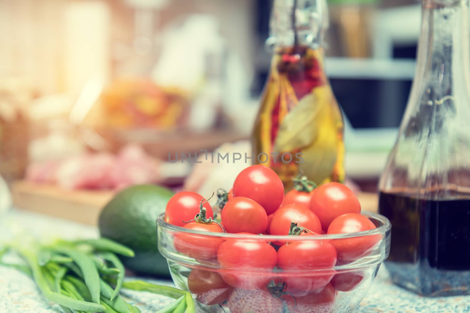 Raw fresh cherry tomatoes in glass bowl in a modern kitchen. Shallow depth of field. Toned