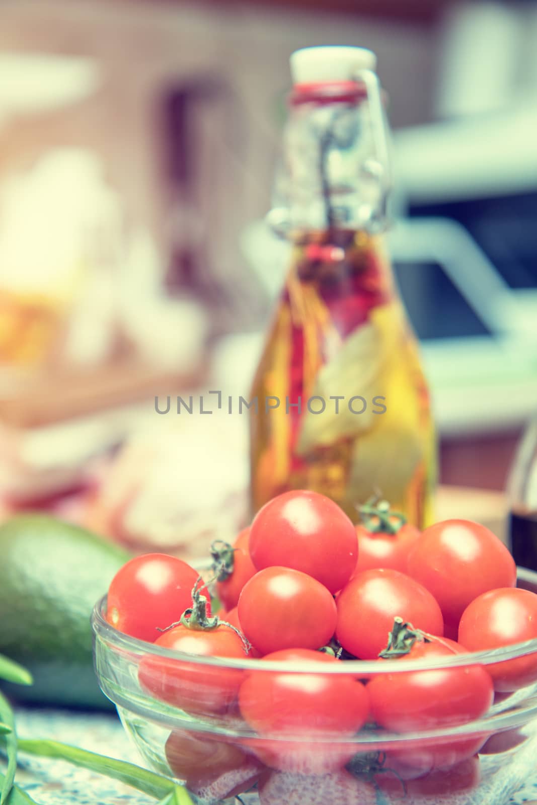 Raw fresh cherry tomatoes in glass bowl in a modern kitchen. Shallow depth of field. Toned