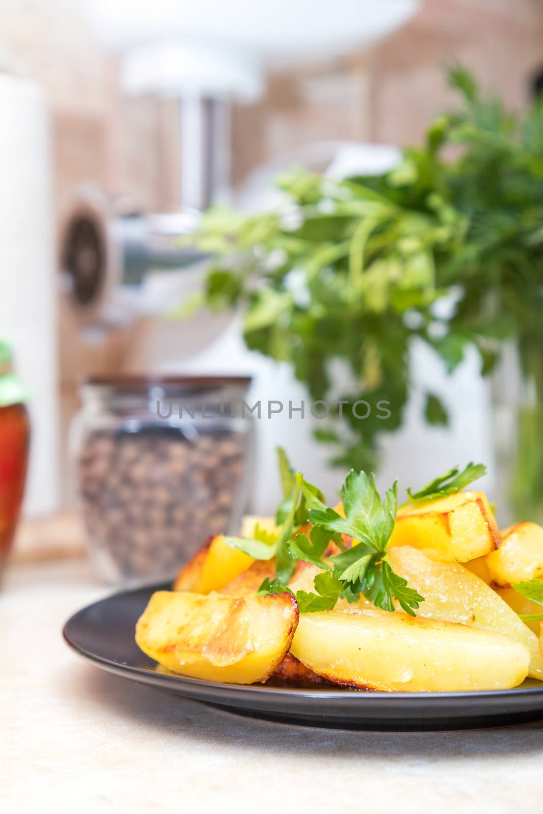 Baked fried potatoes with parsley in black plate by ArtSvitlyna