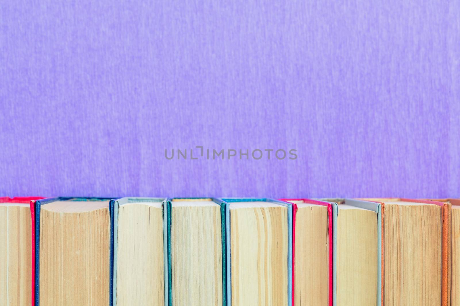 Books background. Many different books on violet wall.