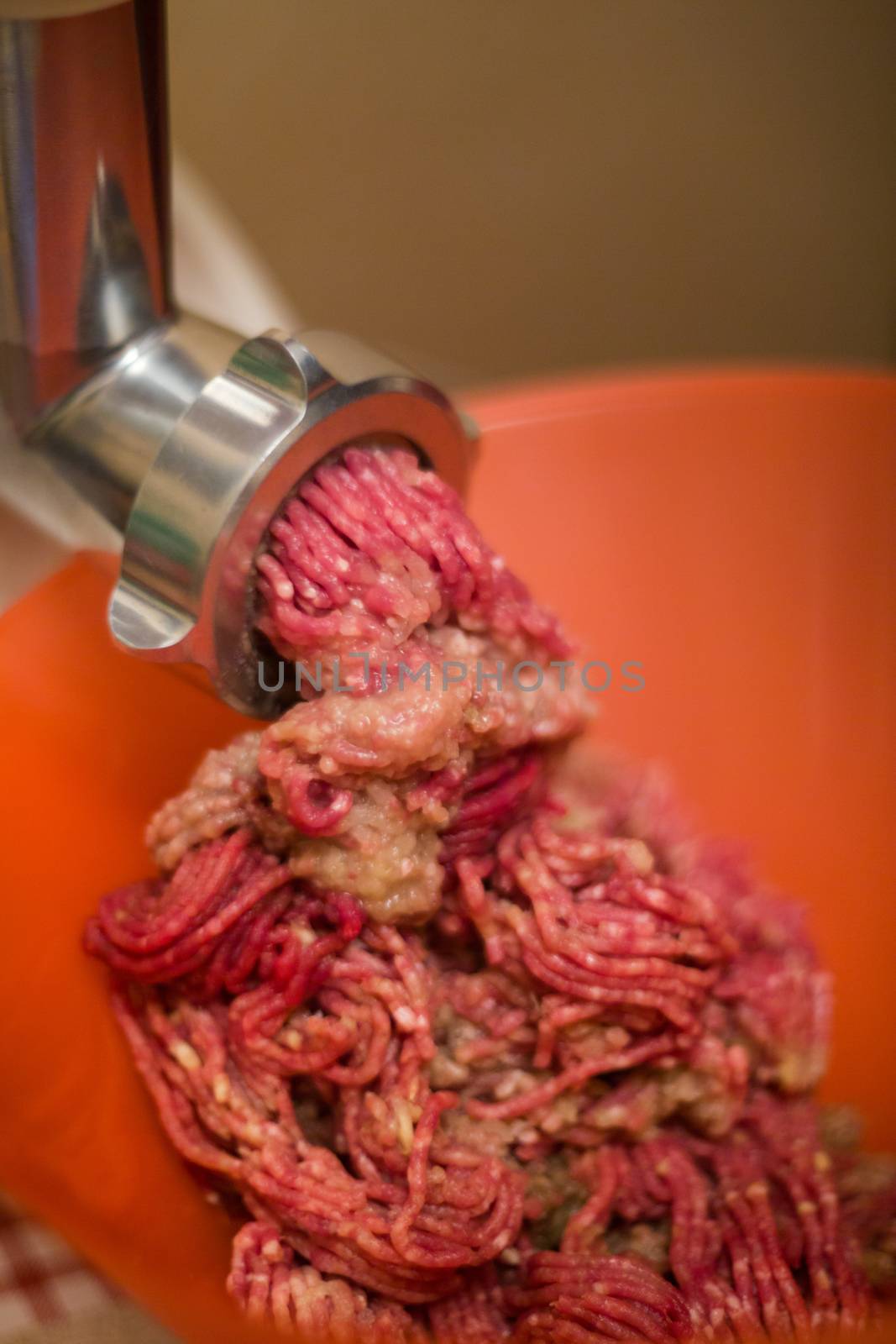 Close up of front part of meat grinder or mincing-machine with mince meat in. Showing the forcemeat process.