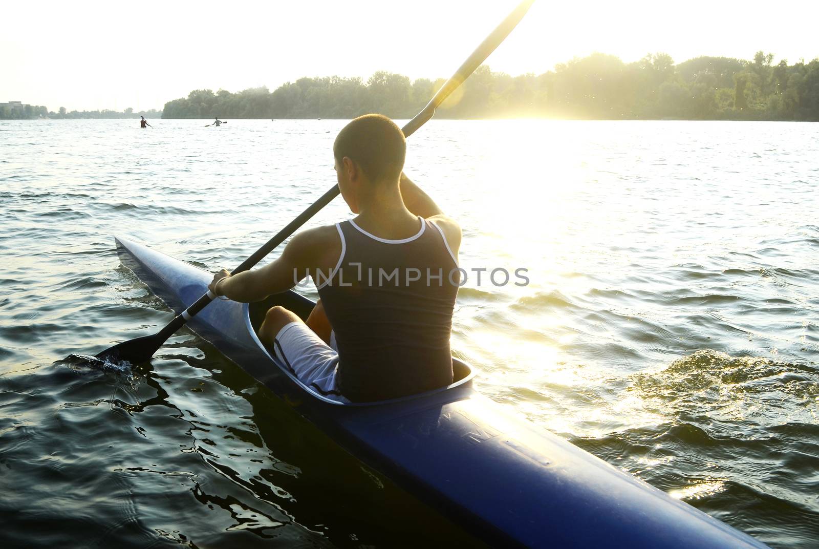 Young people rowing on the river at sunset