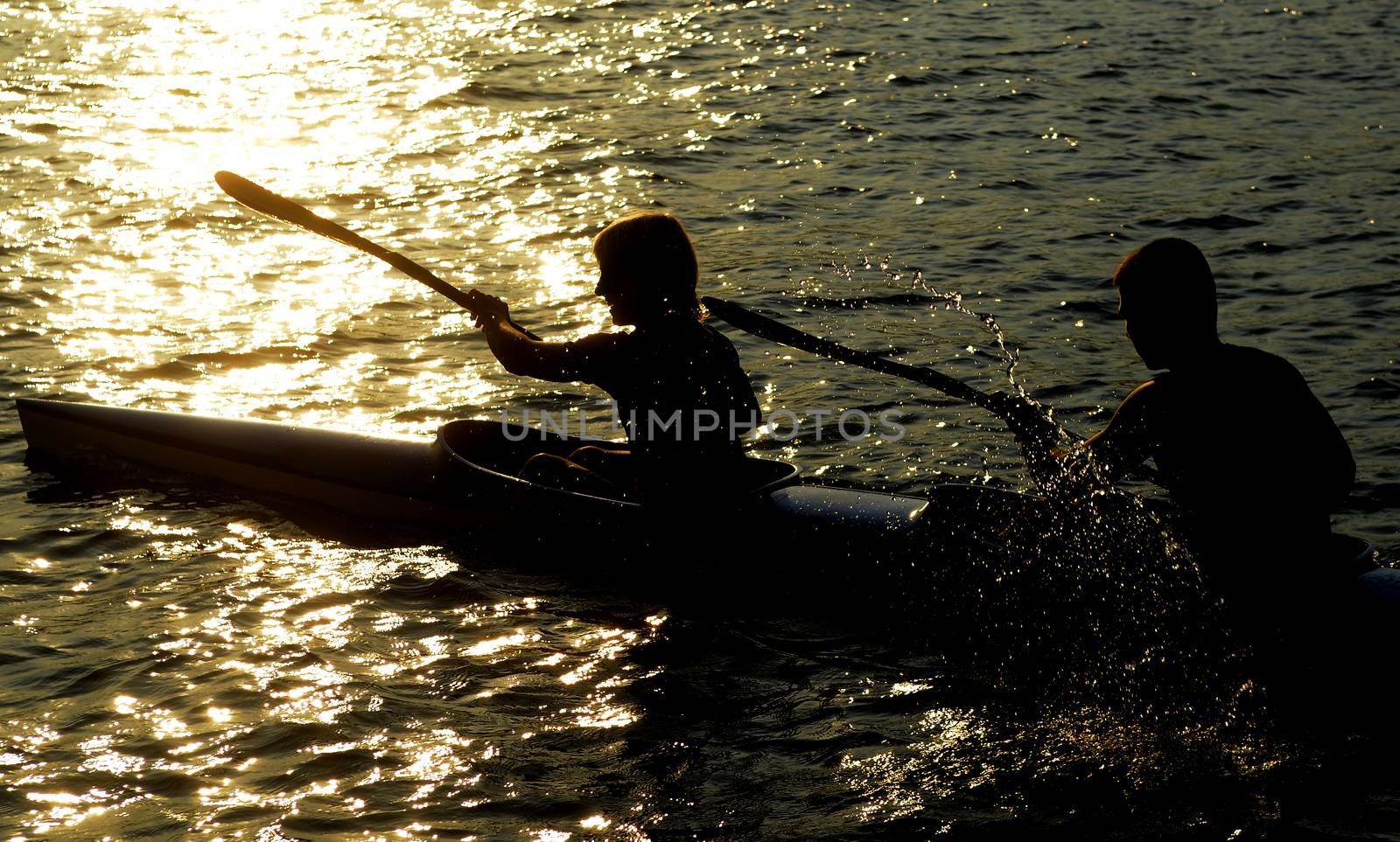 Young people rowing on the river at sunset