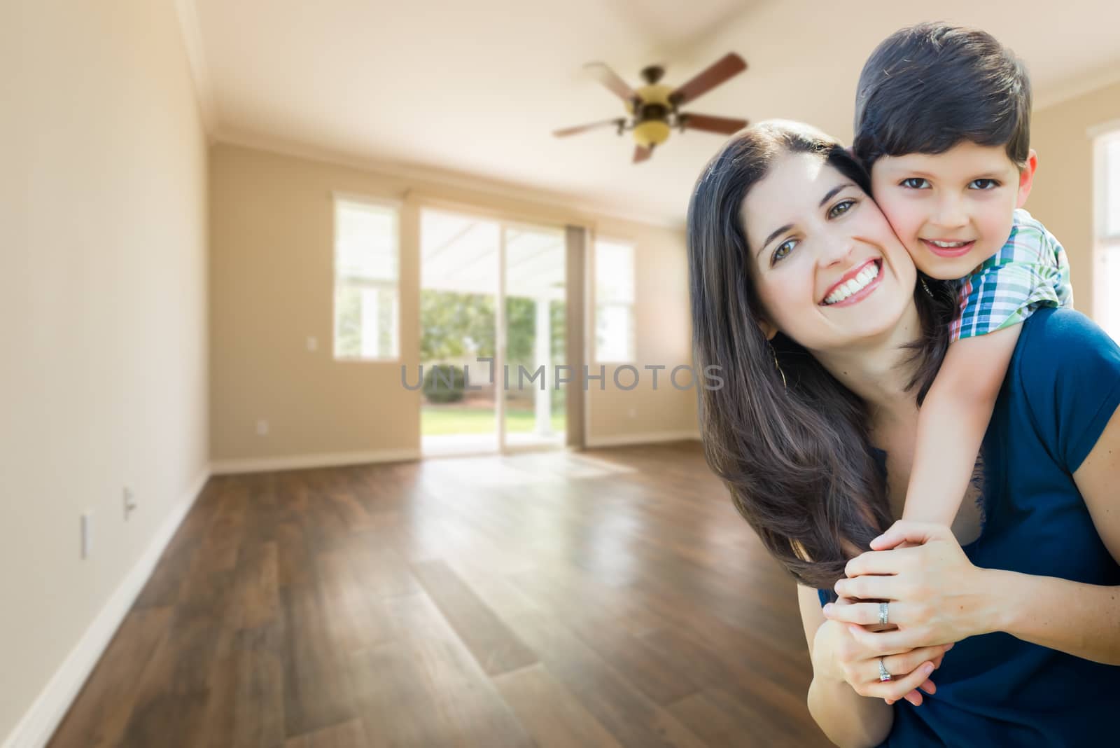 Young Mother and Son Inside Empty Room with Wood Floors.